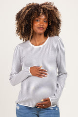 woman wearing a gray and white striped long sleeve maternity top and holding her baby bump