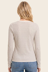 woman wearing a beige and cream striped long sleeve top, viewed from the back, paired with light blue jeans
