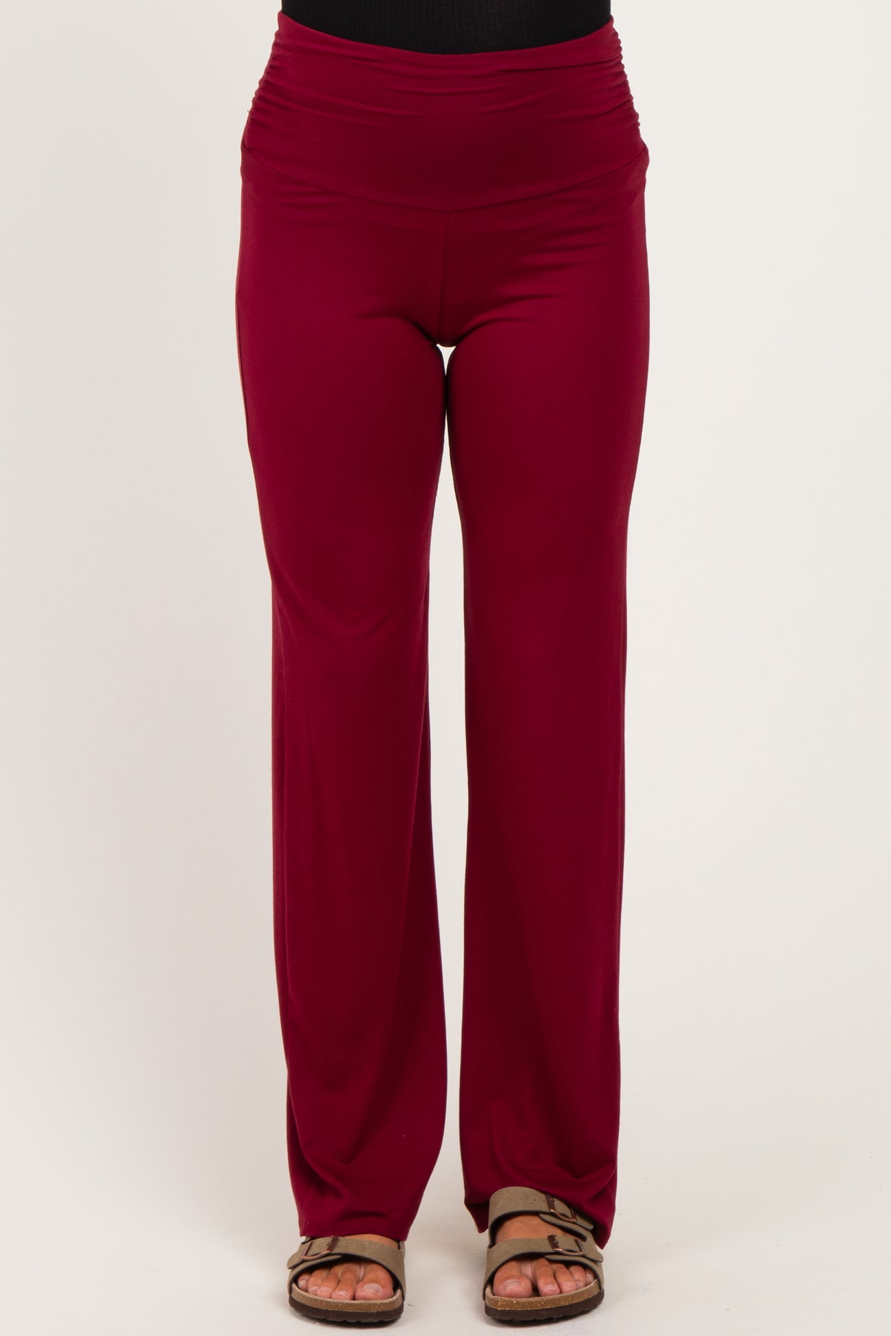 woman wearing burgundy maternity pants with a wide waistband and a relaxed fit