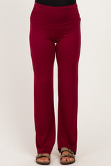 woman wearing burgundy maternity pants with a wide waistband and a relaxed fit