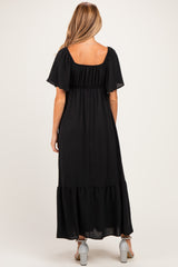 woman wearing a black maternity maxi dress with a square neckline and puff sleeves, showing the back view