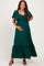 woman wearing a dark green maternity maxi dress with a tie front and flutter sleeves, holding her baby bump