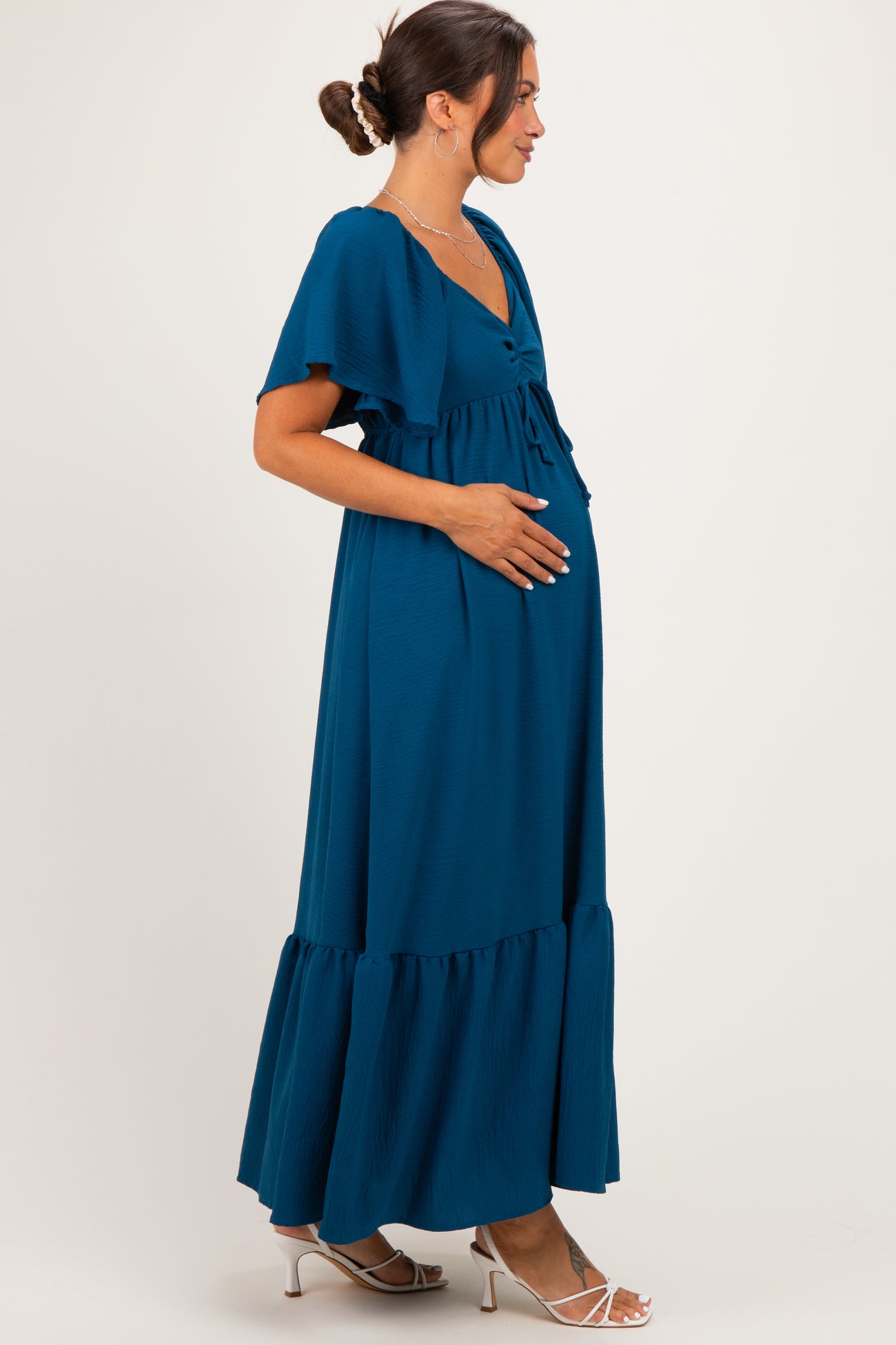 woman wearing a teal maternity maxi dress with flutter sleeves and a baby bump visible
