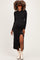 woman wearing a black long sleeve maternity dress with a side slit and showing her baby bump