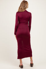 woman wearing a burgundy long sleeve maternity dress showing her baby bump from the back