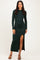 woman wearing a dark green long sleeve maxi dress with a side slit and strappy sandals