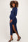 woman wearing a navy blue long sleeve maternity dress with a side slit and showcasing her baby bump