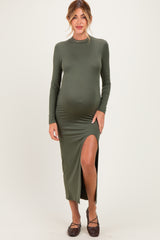 woman wearing a dark green long sleeve maternity dress with a side slit and a visible baby bump