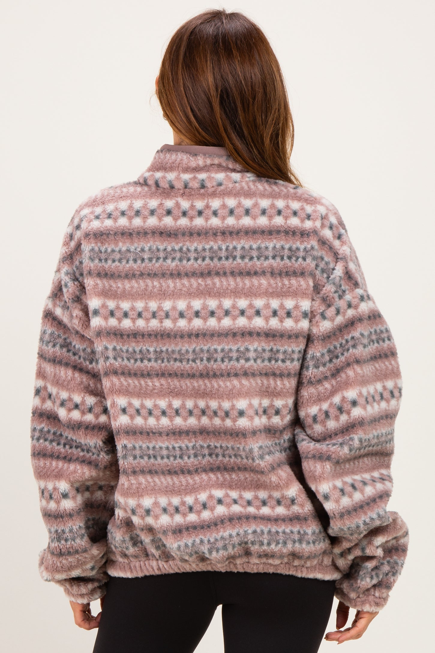 woman wearing a patterned oversized fleece pullover in shades of pink and gray, shown from the back
