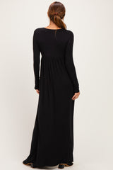 woman wearing a long black maxi dress with long sleeves and a fitted bodice, showing the back view