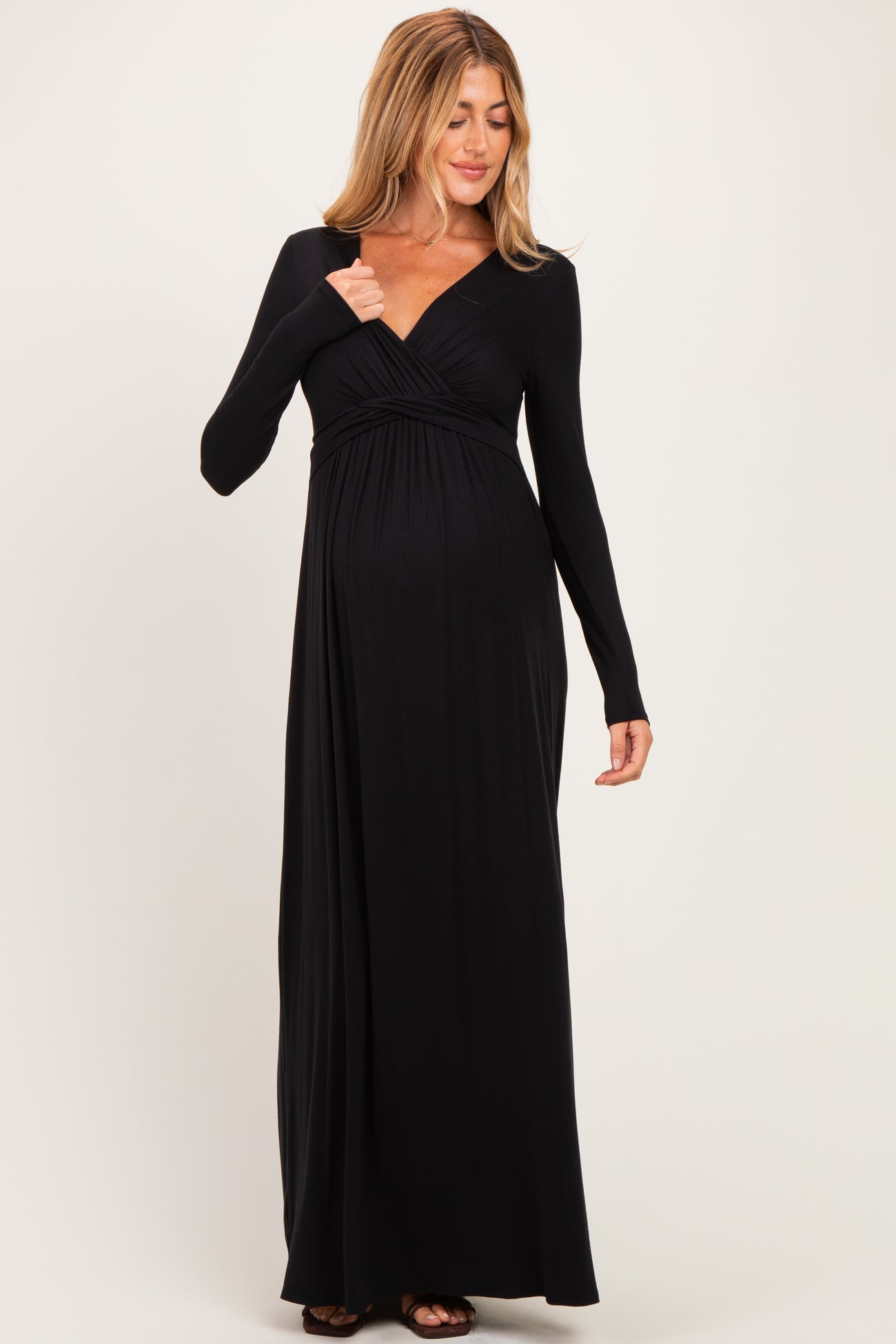 woman wearing a black long sleeve maternity maxi dress, gently highlighting her baby bump