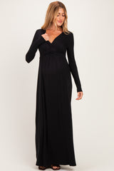 woman wearing a black long sleeve maternity maxi dress, gently highlighting her baby bump