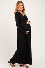 woman wearing a black long sleeve maternity dress and cradling her baby bump