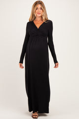 woman wearing a black long sleeve maternity maxi dress with a twisted front detail and a visible baby bump