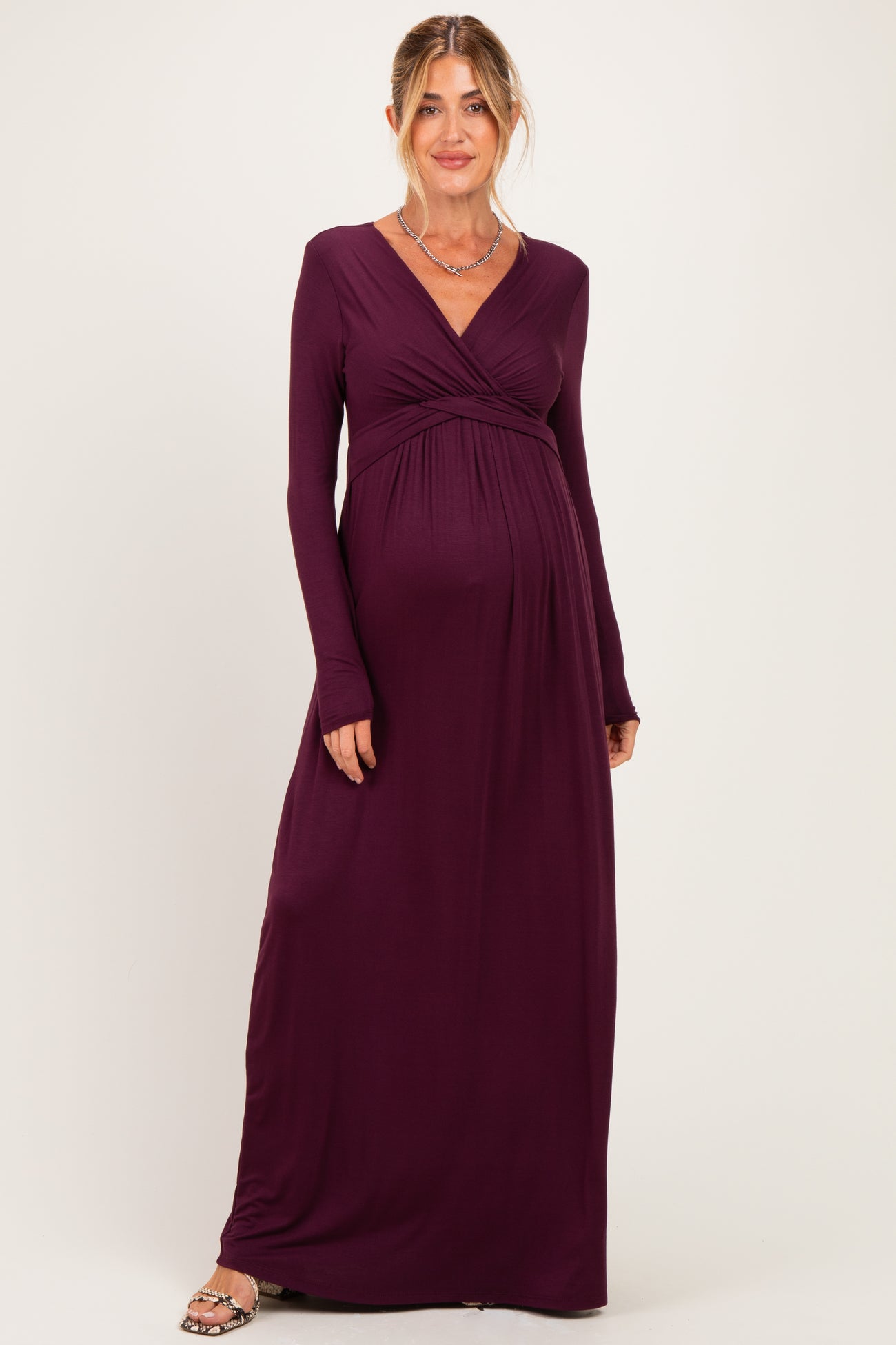 woman wearing a dark purple long sleeve maternity dress with a wrap-style bodice and baby bump visible
