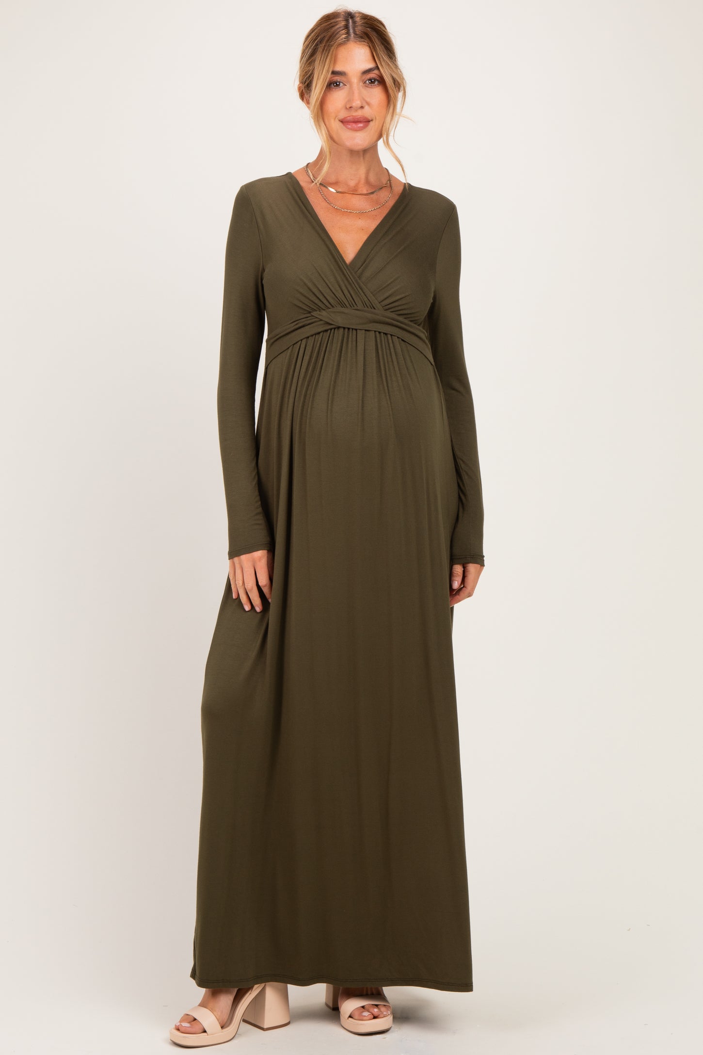 woman wearing an olive green long sleeve maternity dress with a v-neck and empire waist, showcasing her baby bump