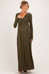 woman wearing an olive green long sleeve maternity dress with a fitted bodice and flowing skirt, showing her baby bump