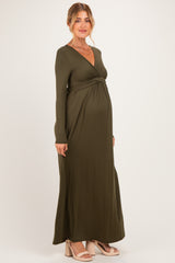 woman wearing a dark olive green long sleeve maternity dress with a twist detail and visible baby bump