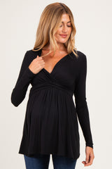 woman wearing a black long sleeve maternity top with a wrap design and a visible baby bump