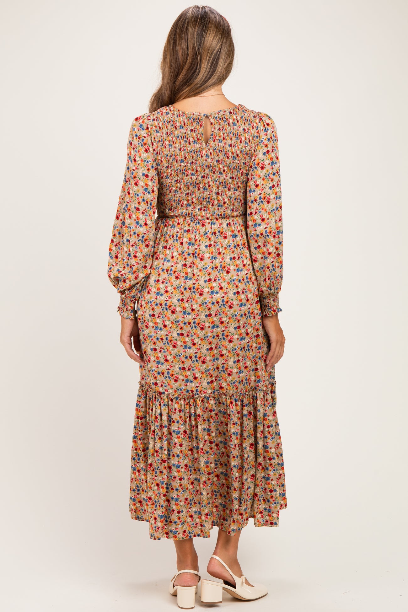 woman wearing a floral long sleeve maternity dress with a smocked bodice and tiered skirt, showing the back view