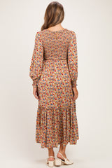 woman wearing a floral long sleeve maternity dress with a smocked bodice and tiered skirt, showing the back view