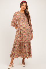 woman wearing a floral pattern maternity maxi dress with puff sleeves and pockets, featuring a smocked bodice
