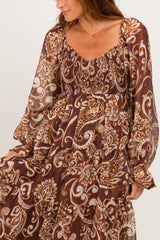 woman wearing a brown paisley print long sleeve dress with tiered ruffles and a smocked bodice