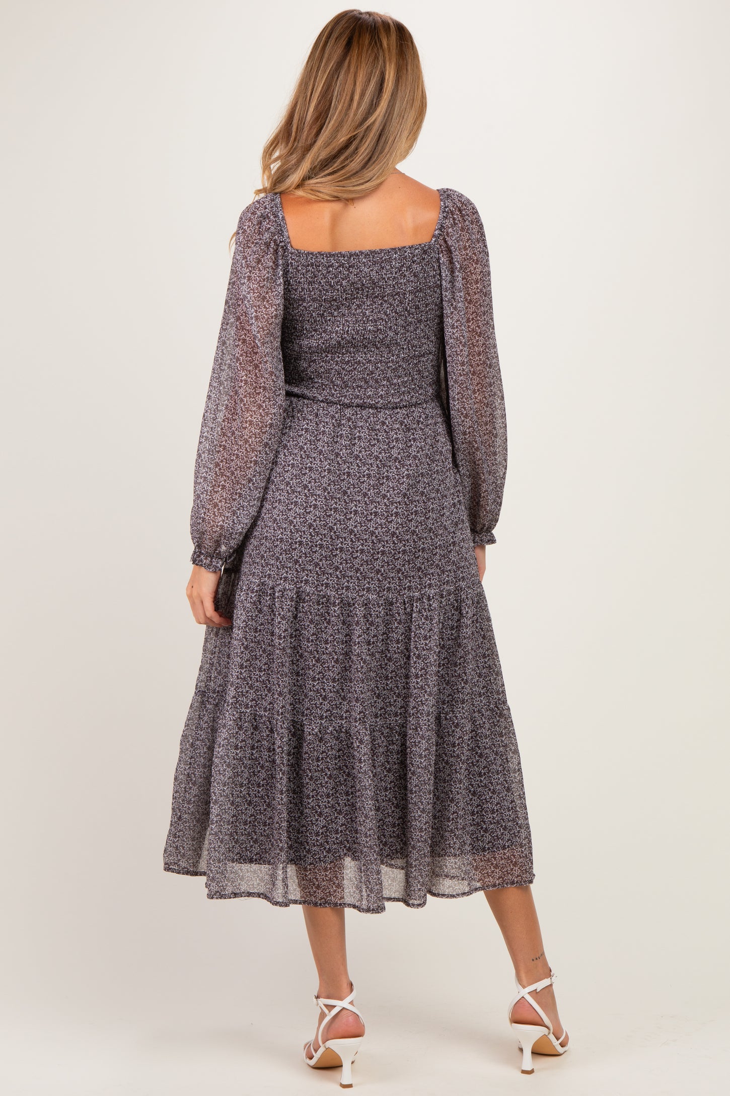 woman wearing a tiered floral maternity dress with long puff sleeves and a square neckline, showing her baby bump