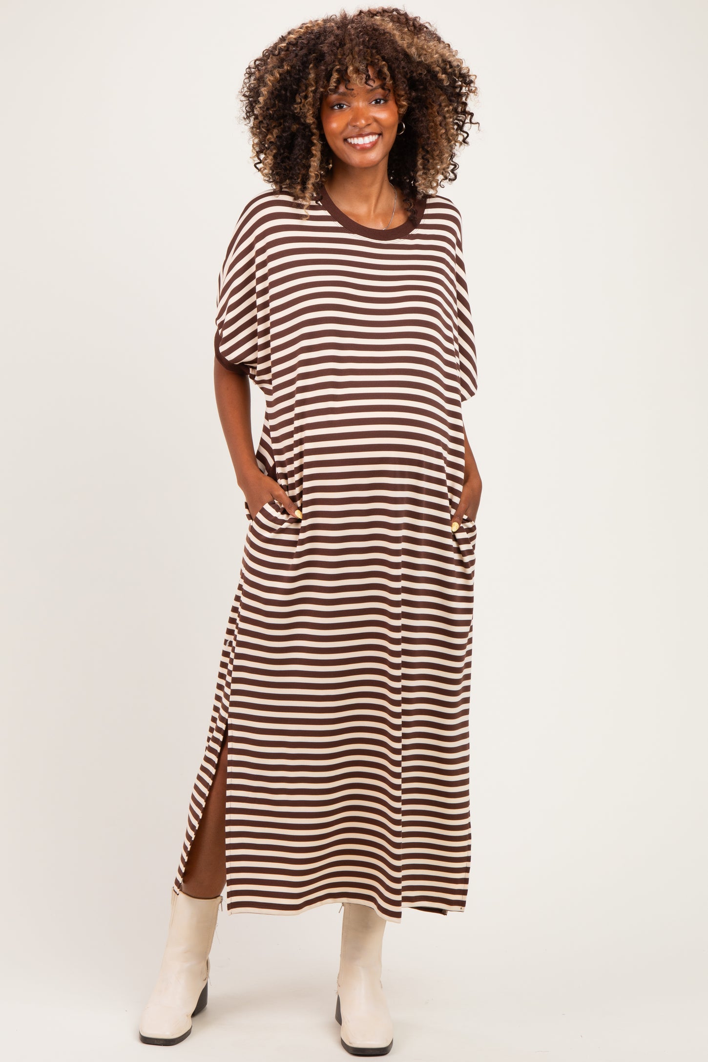 woman wearing a brown and white striped maternity maxi dress with short sleeves and pockets, showing her baby bump