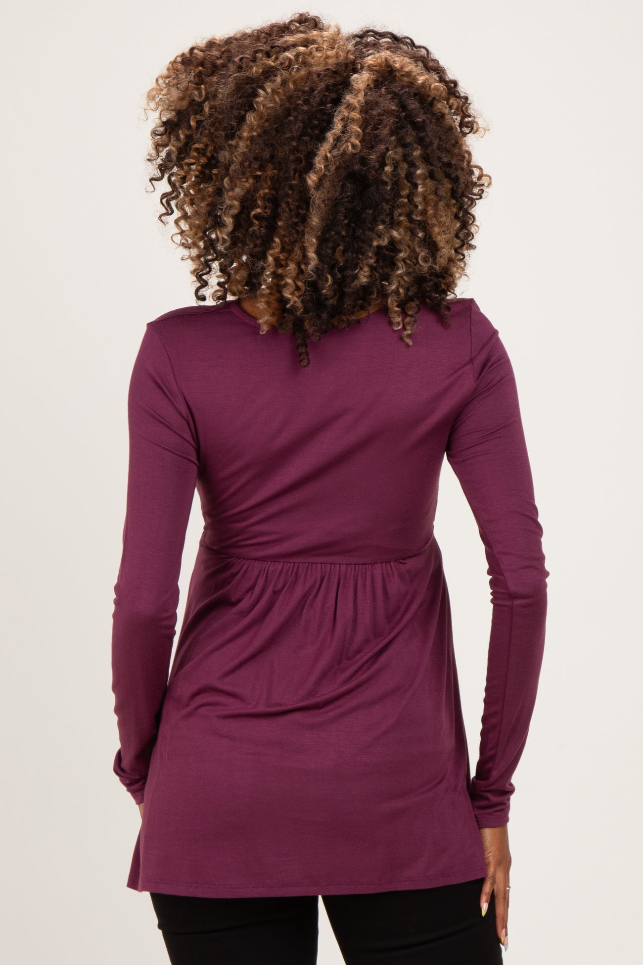 woman wearing a dark plum maternity top with a cinched waist and long sleeves, viewed from the back
