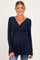 woman wearing a navy blue long sleeve maternity top with a twisted front detail and visible baby bump
