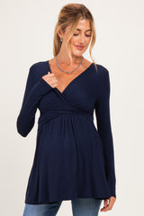 woman wearing a navy blue long sleeve maternity top with a wrap design and a visible baby bump