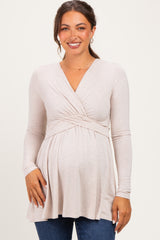 woman wearing a light beige long sleeve maternity top with a wrapped design and visible baby bump