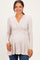 woman wearing a light beige long sleeve maternity top with a wrapped design and visible baby bump
