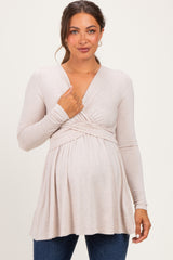 woman wearing a light beige long sleeve maternity top with a wrap style and baby bump visible