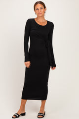 woman wearing a black long sleeve maxi dress with a knot detail at the waist and styled with black sandals