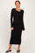 woman wearing a black long sleeve maxi dress with a knot detail at the waist and styled with black sandals