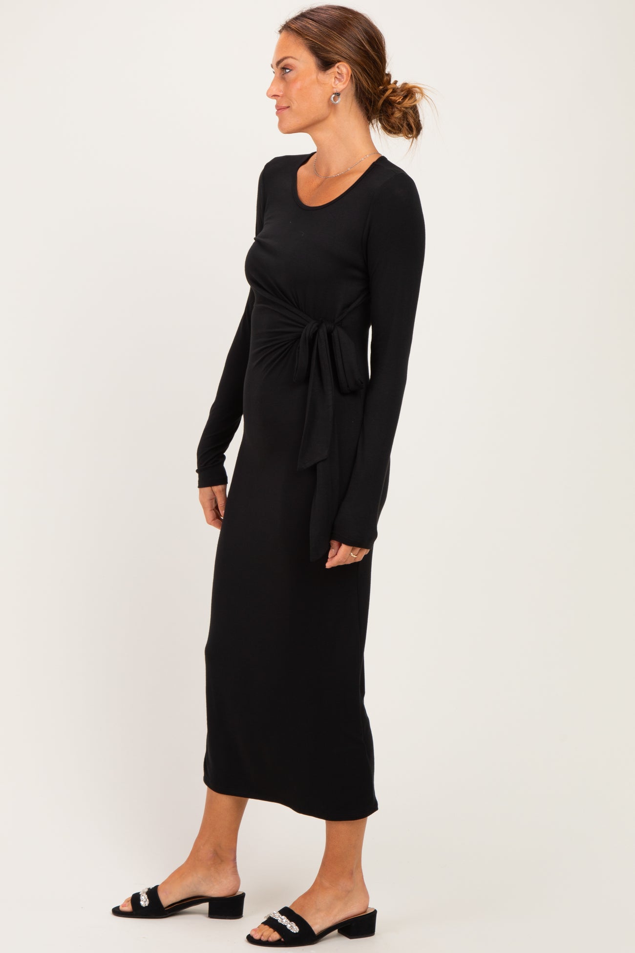 woman wearing a black long sleeve maxi dress with a front tie detail and ankle-length hem