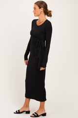 woman wearing a black long sleeve maxi dress with a front tie detail and ankle-length hem