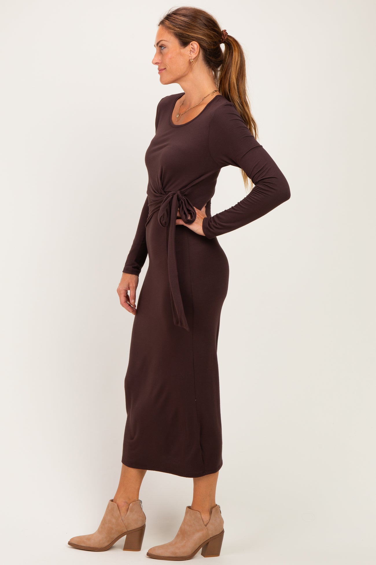 woman wearing a brown long sleeve tie-waist midi dress and beige ankle boots