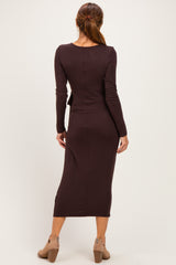 woman wearing a brown long sleeve fitted dress with a midi length and a back slit, standing and facing away from the camera