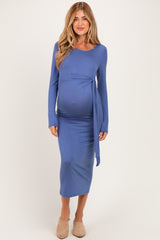 woman wearing a blue long sleeve maternity dress with a tied waist and visible baby bump
