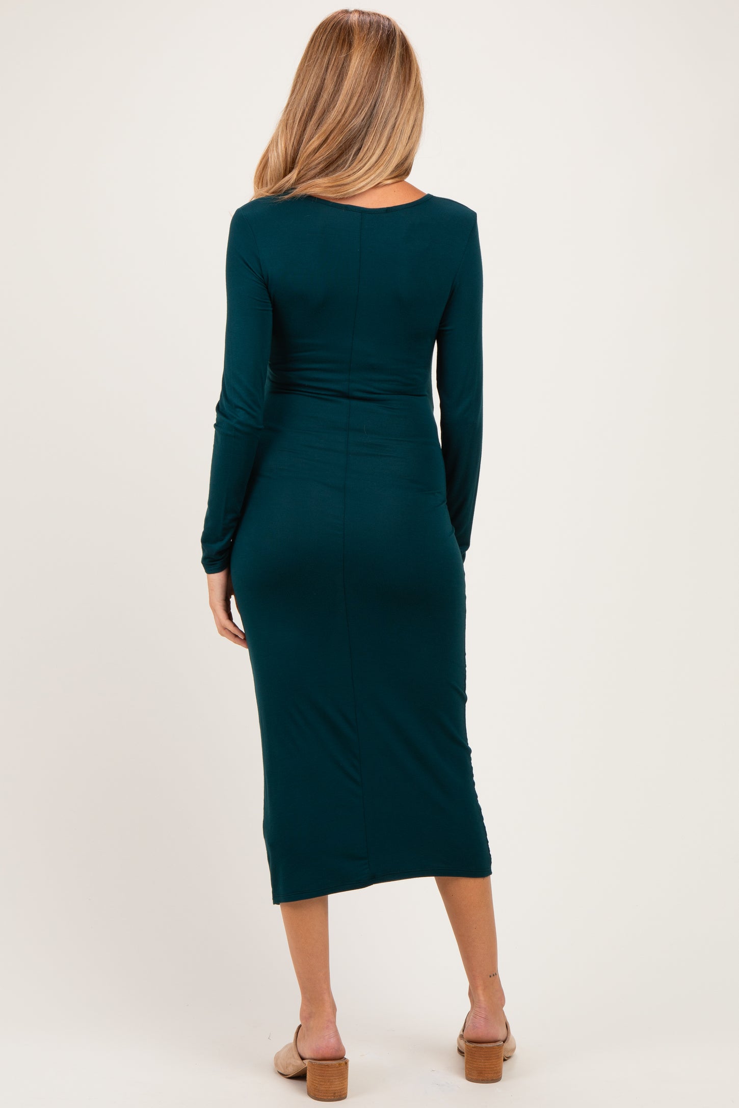 woman wearing a dark teal long sleeve maternity dress that hugs the body and falls to mid-calf, showing a baby bump