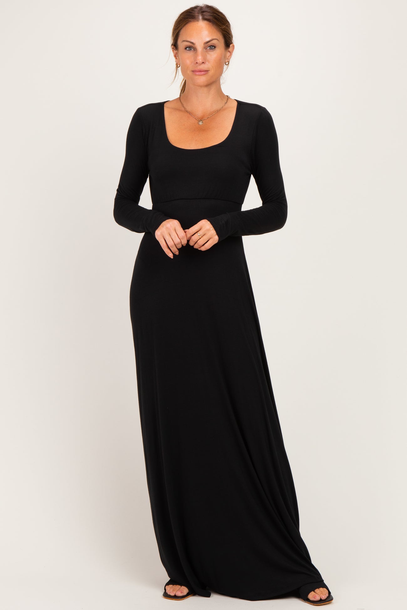 woman wearing a black long sleeve maxi dress with a scoop neckline and fitted bodice