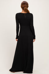 woman wearing a fitted black long sleeve maxi dress, showing the back view and flowing skirt