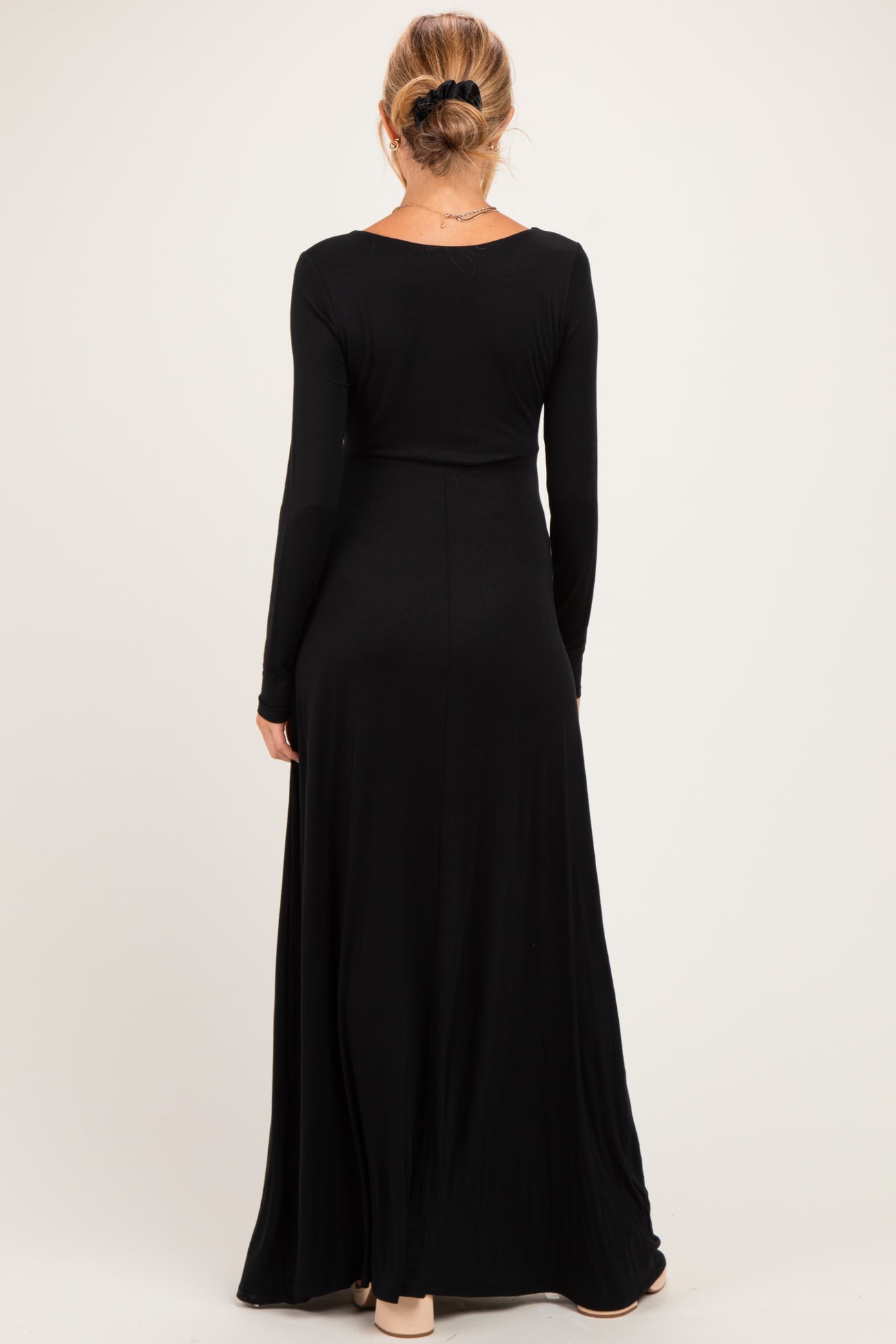 woman wearing a black long sleeve maternity maxi dress, view from the back, showcasing a flowing skirt design