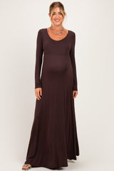 woman wearing a long sleeve brown maternity dress with a fitted bodice and flowy skirt, baby bump visible