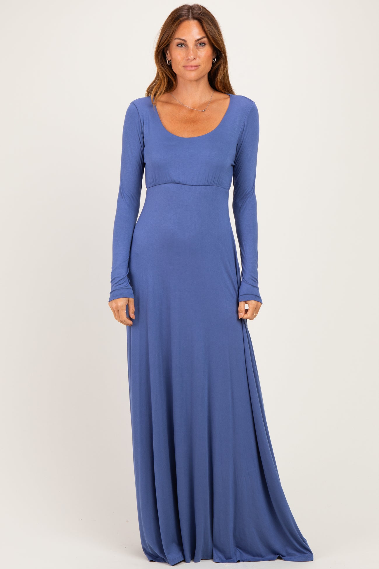 woman wearing a long sleeve blue maxi dress with a scoop neckline and fitted waist detail