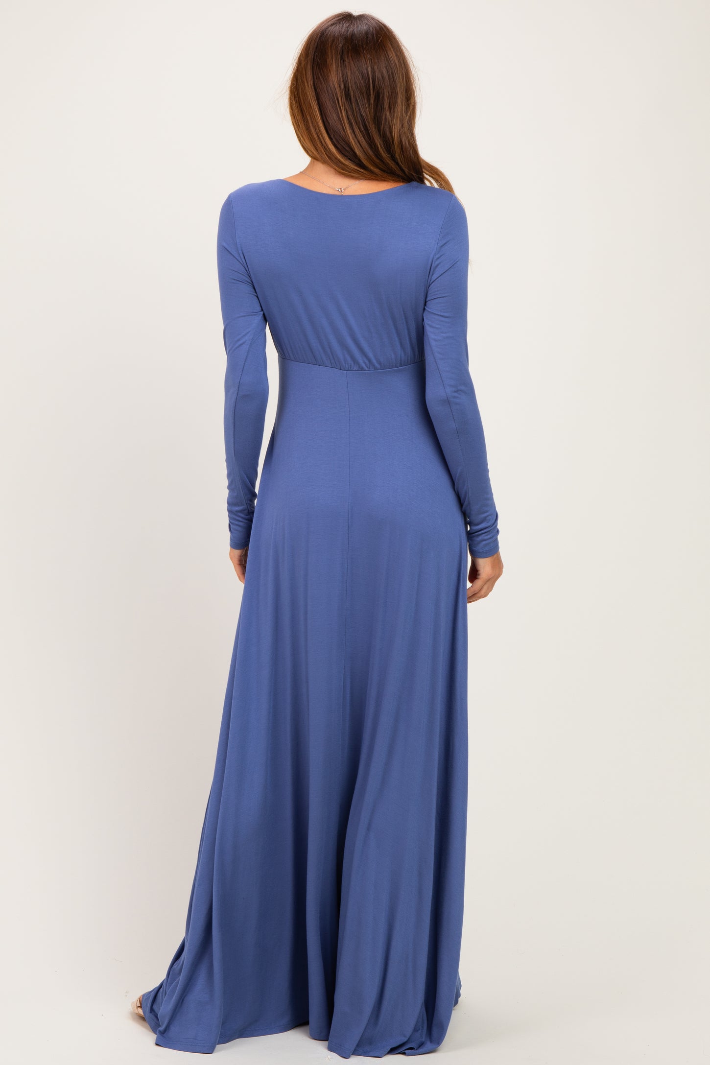 woman wearing a long sleeve blue maxi dress, showcasing a flowing silhouette from the back