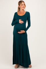 woman wearing a dark teal long sleeve maternity dress and holding her baby bump
